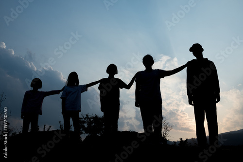 Group of happy children playing at sunset, silhouette