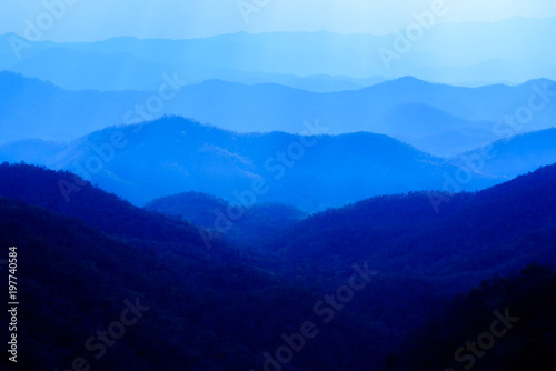 Canvas Print Beautiful landscape of blue mountains layers during sunset with sunrays