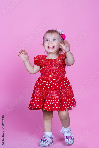 little girl laughing on a pink background in the studio