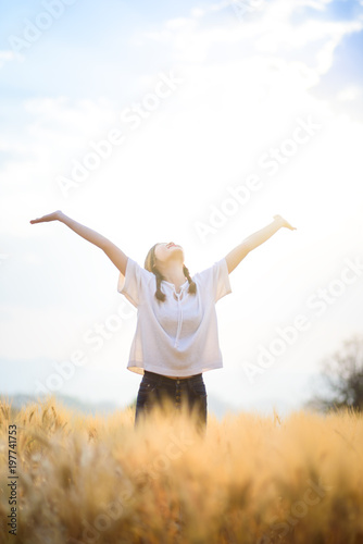 Happy woman relaxing on wheat field in summer sunset sky outdoor. People freedom open arms