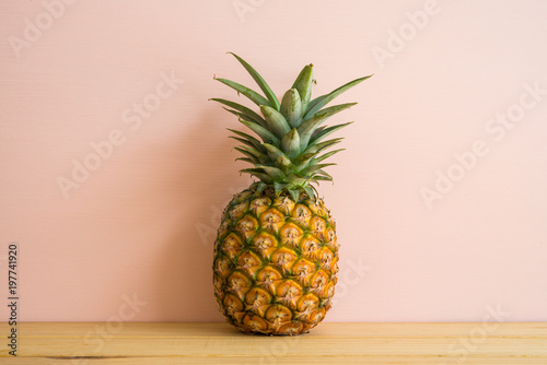 Organic pineapple on pink wooden background with copy space, tropical summer holiday vacation concept