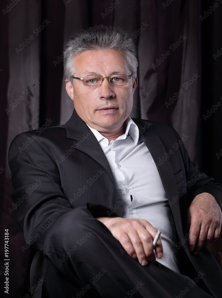 Fototapeta premium senior businessman with a cigarette,sitting in a chair