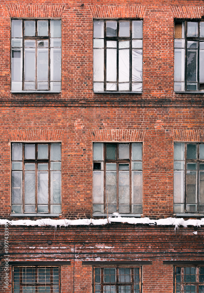 Obraz premium Winter facade of an old brick building in loft style. High Windows and textural materials