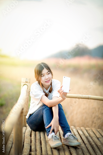 happy young asian woman taking selfie form smartphone during summer Sunset with landscape background