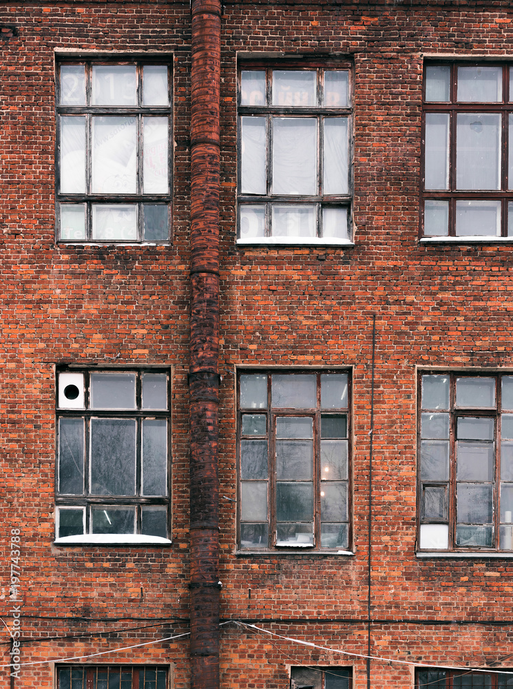 Obraz premium Facade of an old brick building in loft style. High Windows and textural materials.