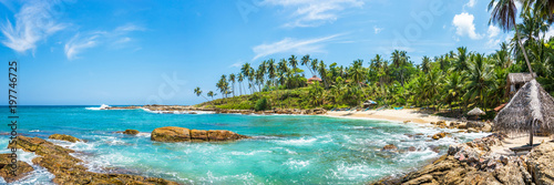 Panoramic view of a small lagoon with traditional wooden fishing boats and old bungalow on the beach in Sri Lanka.