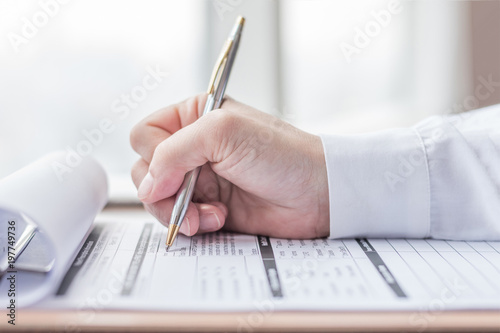 Applicant filling in company application form document applying for job, or registering claim for health insurance photo