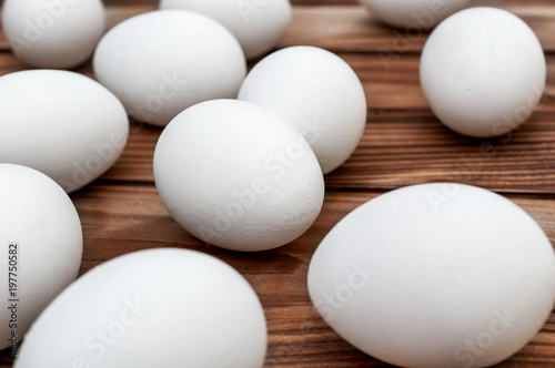 White eggs on the brown wooden table.