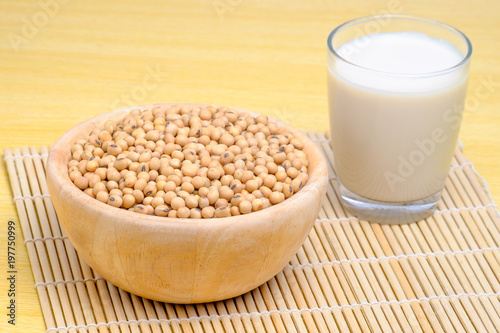 soy milk in glass and soy seeds in wooden bowl