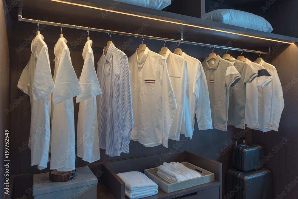 row of white shirts on rail in wooden closet