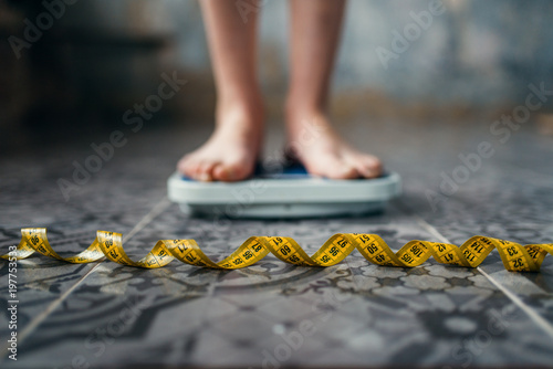 Female feet on the scales, measuring tape