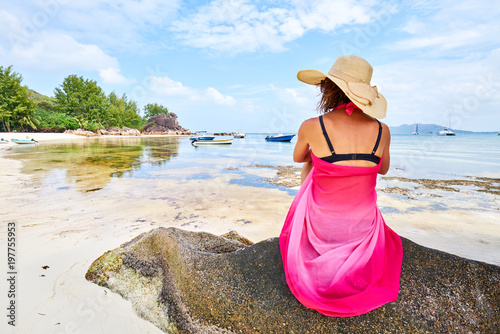 Women is sitting on a rock on the beach of a tropical island, curieuse island, excursion day, adventure episod photo