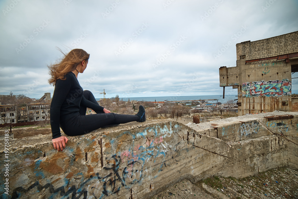 Young slim brunette on a ruins of abandoned building