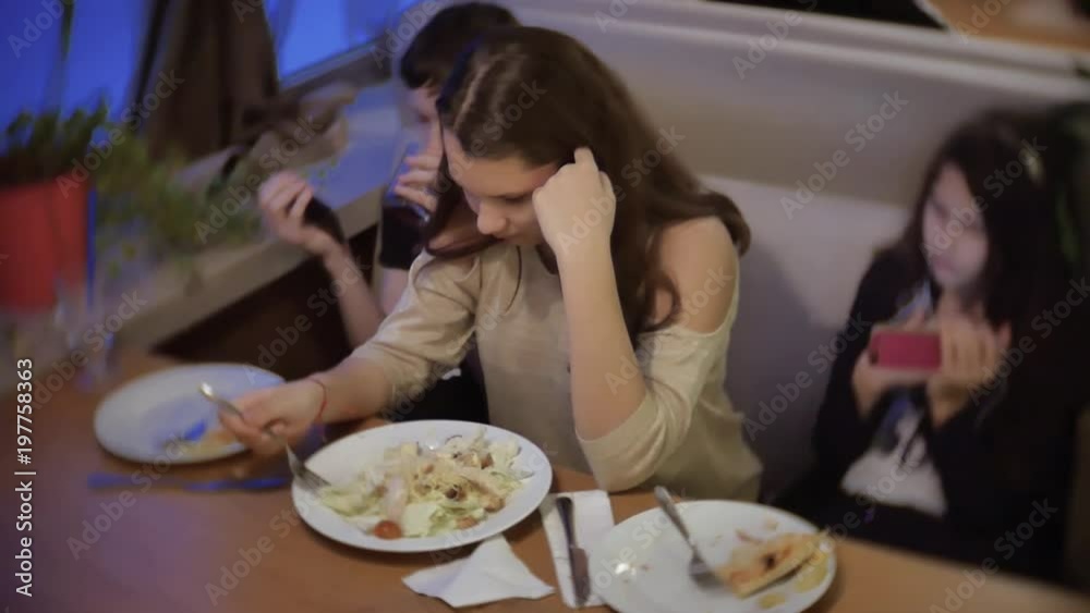 girl teen eating a salad in a fast food cafe. Group of friends sitting indoors dinner at cafe girl teen eating a salad in a fast food cafe. Group of friends sitting indoors dinner at cafe
