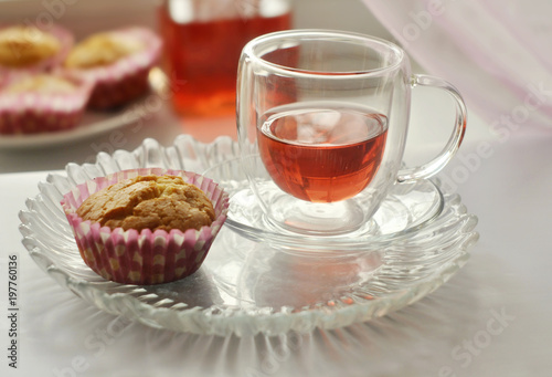 Homemade muffin and red juice in a glass cup on a white table. Close-up. 