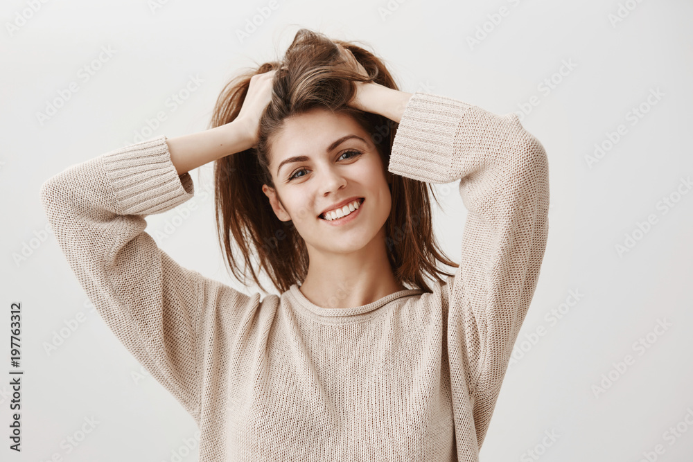 Girl feels like she need to visit hairdresser. Portrait of carefree attractive female with broad smile lifting hair up with hands, and tilting, being home and making bun to prepare dinner Girl feels like she need to visit hairdresser. Portrait of carefree attractive female with broad smile lifting hair up with hands, and tilting, being home and making bun to prepare dinner
