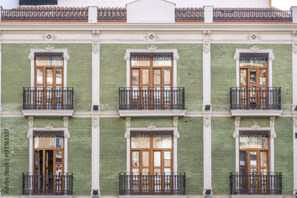 several windows of apartment residential building early twentieth century green colorful face brick facade at typical neighborhood, traditional, vintage apartment architecture several windows of apartment residential building early twentieth century green colorful face brick facade at typical neighborhood, traditional, vintage apartment architecture