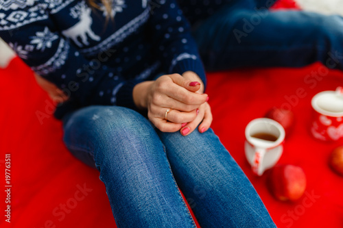 Young loving couple warm sweaters and jeans, hugging, sitting on a red blanket. Boyfriend and girlfriend traveling lifestyle, tranquility and contemplation on a cold winter vacation. Winter nature.