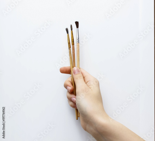 Three watercolor brushes that the hand holds
