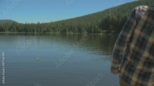 Young man skipping some rocks on a lake