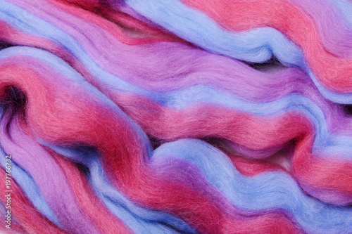 Bright colored merino wool for felting and needlework, hobby. The stripes of pink, blue and violet color yarn folded into abstract pattern. Abstract art background