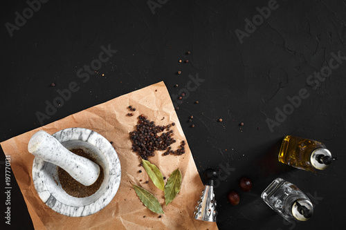 White mortar and pestle with dried peppers in flat lay on black background photo