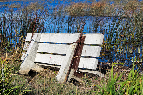 A cement bench flooded out and sinking into a marsh