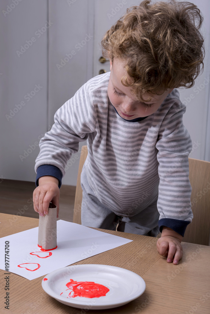 Child painting hearts with a wC paper carton Child painting hearts with a wC paper carton