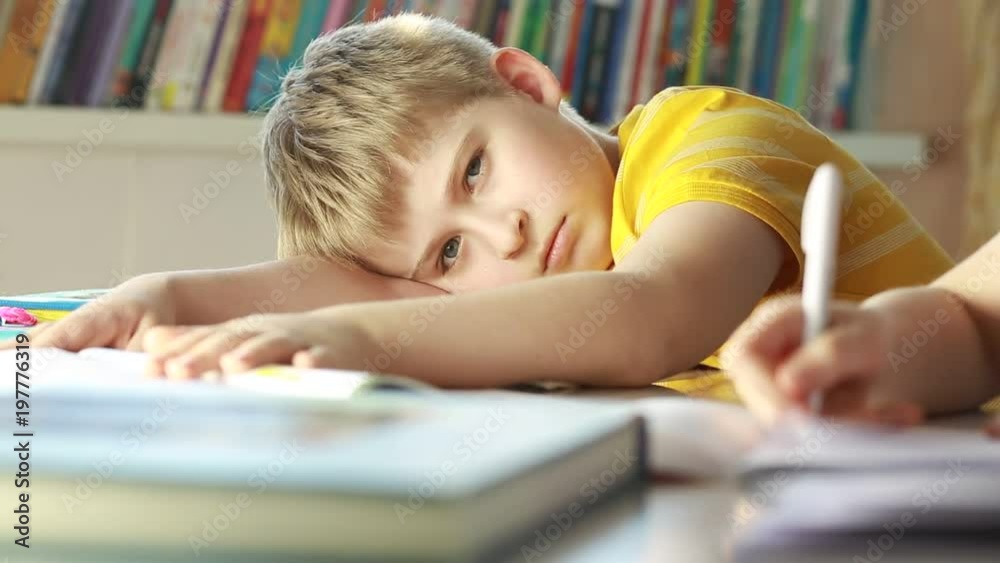 Tired and exhausted primary school student falling asleep while studying. Tired and exhausted primary school student falling asleep while studying.