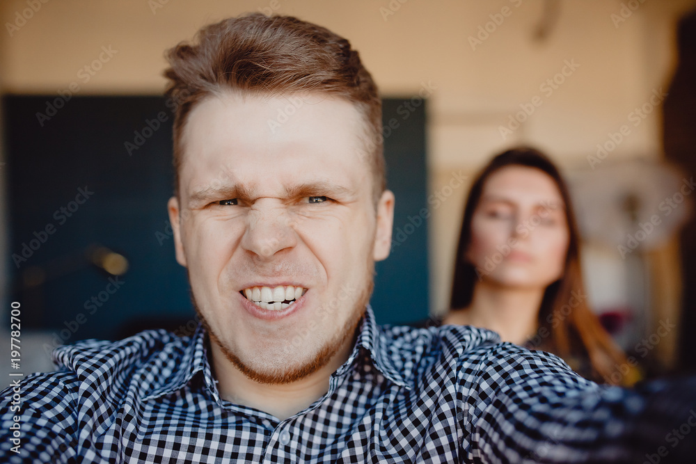 Young couple makes selfie photo on camera, man is angry, woman is offended. Concept of problem in relations