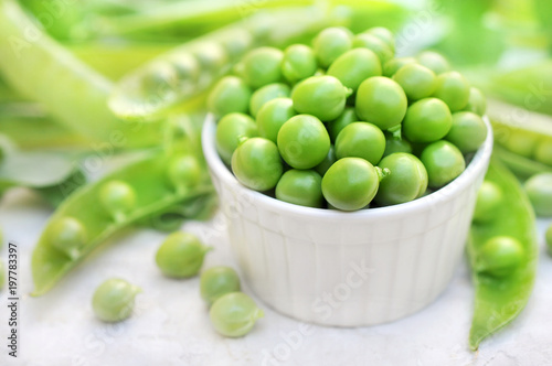 Bowl of fresh harvested green peas on pods background, selective focus
