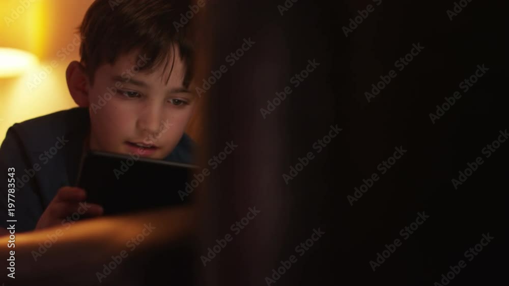 Young boy using tablet while lying down on couch at home. 4k Dolly shot. Young boy using tablet while lying down on couch at home. 4k Dolly shot.