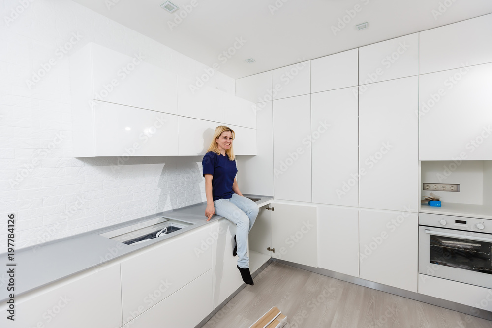 Kitchen repair girl helping to assemble a kitchen in a new home Kitchen repair girl helping to assemble a kitchen in a new home