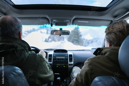 Two men ride an off-road car through the mountains on a snow serpentine
