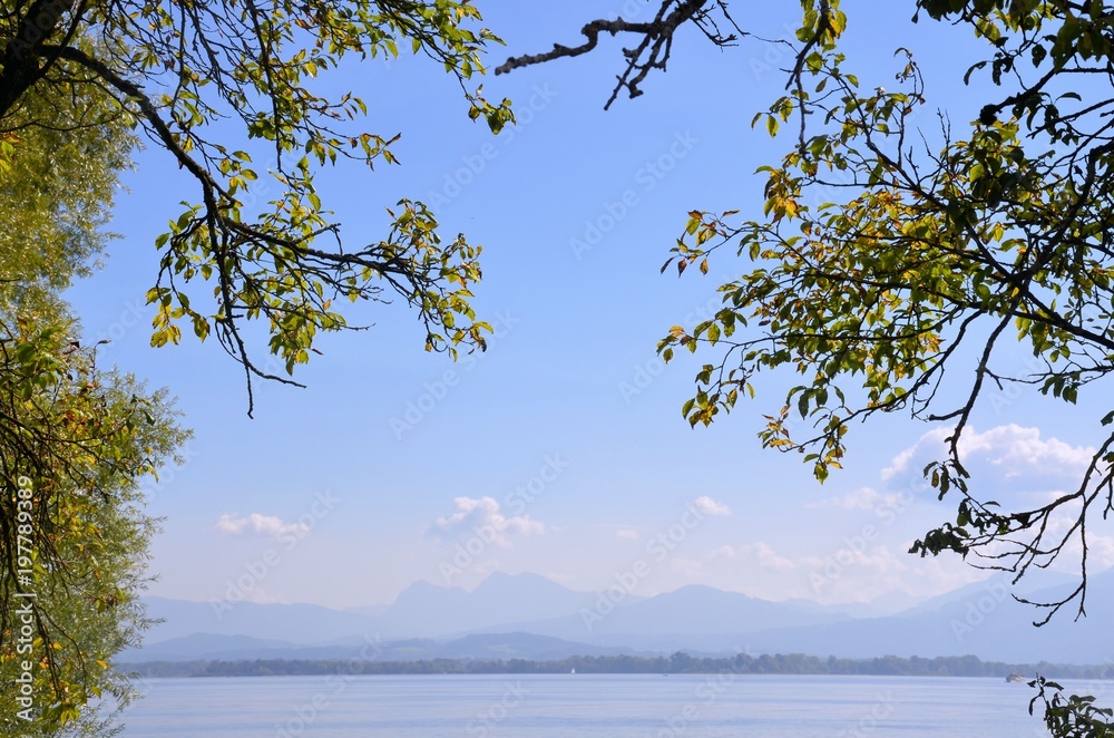 Ausblick über den Chiemsee mit Bergen und Zweigen im Vordergrund Ausblick über den Chiemsee mit Bergen und Zweigen im Vordergrund
