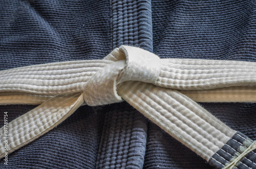 White belt of Brazilian Jiu-Jitsu with four degrees, tied in the kimono, knot of belt.