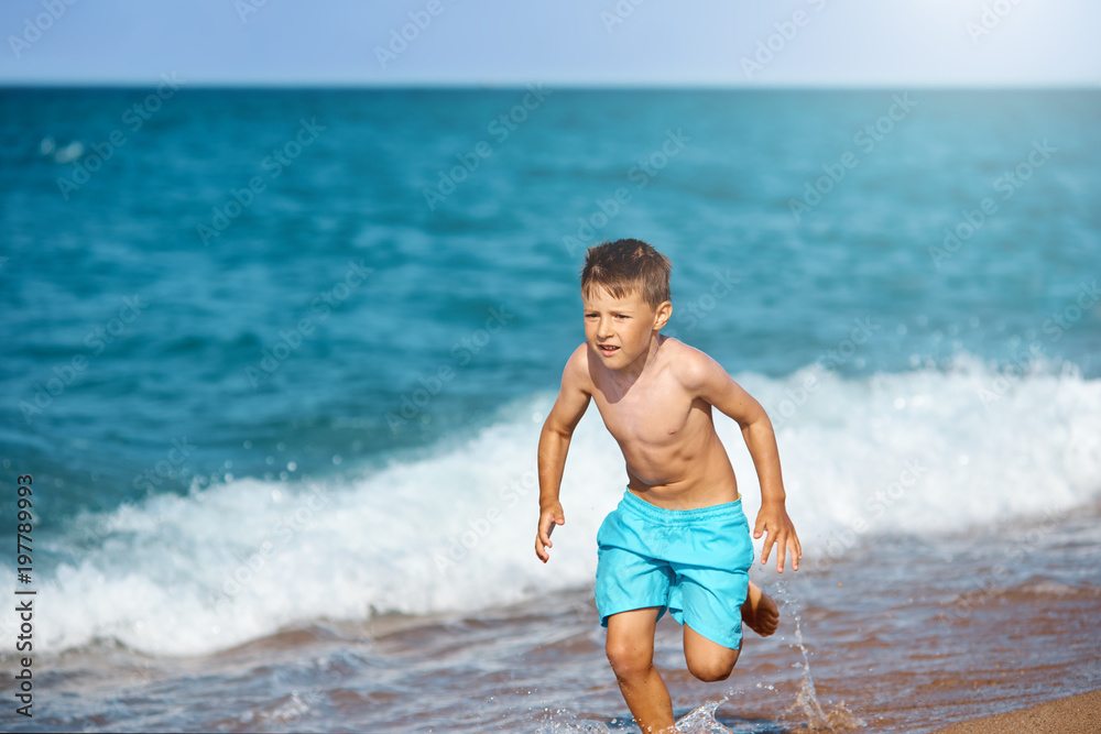 Fototapeta premium European boy is running along the seacost.