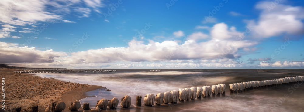 Panorama of a beautiful winter landscape with frozen wooden breakwater at the Baltic Sea. Concept holidays and travel - obrazy, fototapety, plakaty 