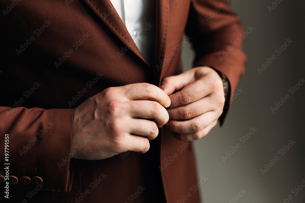 closeup of the groom for pinching a stylish brown jacket