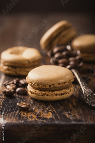 French coffee macaroons with ganache filling with coffee beans on old wooden board on vintage background. Holidays food concept.