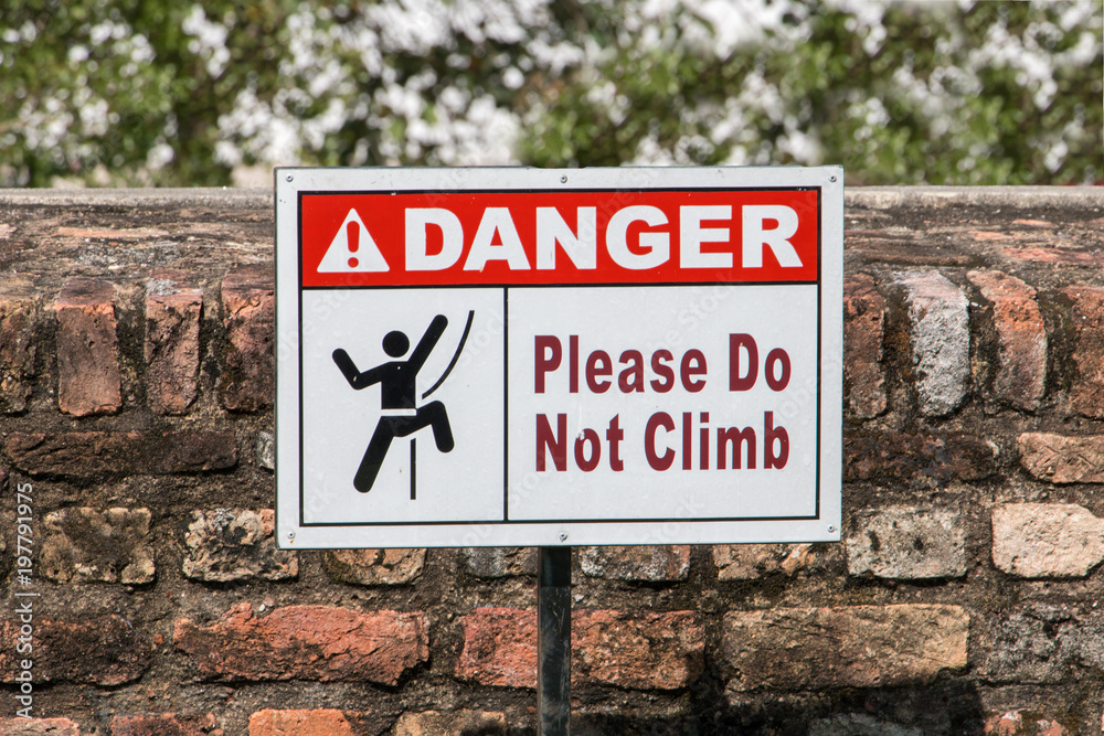 Signs with a ban on climbing the brick wall.