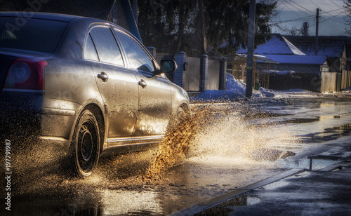 The car drives through a puddle, splashing water