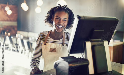 Foto African waitress laughing while working in a trendy restaurant