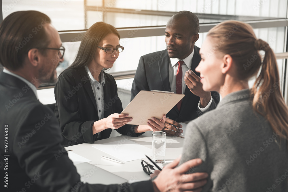 Group of people sitting at the meeting. Focus on man and woman looking at papers Group of people sitting at the meeting. Focus on man and woman looking at papers