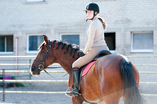 Young lady riding a horseback at equestrian farm