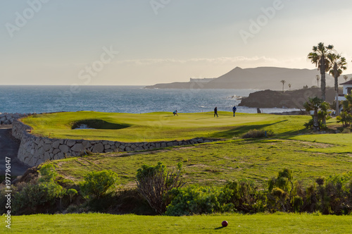 Golf players on a green facing the Atlantic Ocean on the island of Tenerife in Spain photo