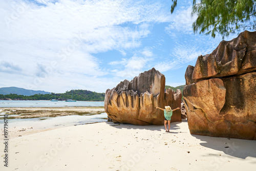 female tourist is walking on Laraie Bay's beach with granite rock, curieuse island, seychelles