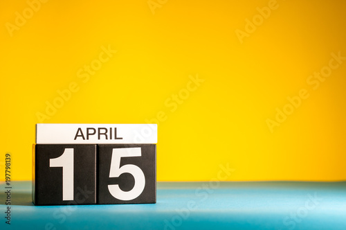 April 15th. Day 15 of april month, calendar on table with yellow background. Spring time, empty space for text