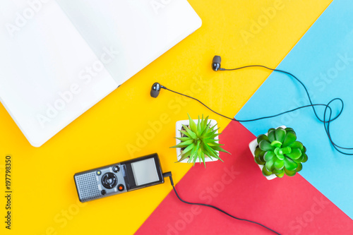 Fotografie Dictaphone with headphones next to green succulents and white notebook