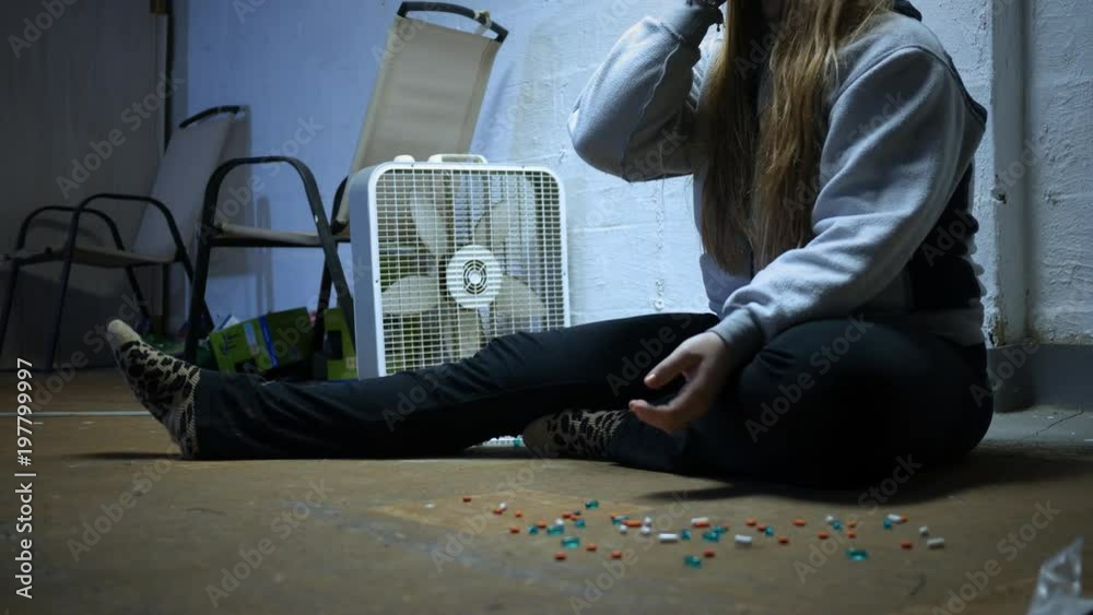 A Woman picks up a pill from the ground and swallows it in trap house